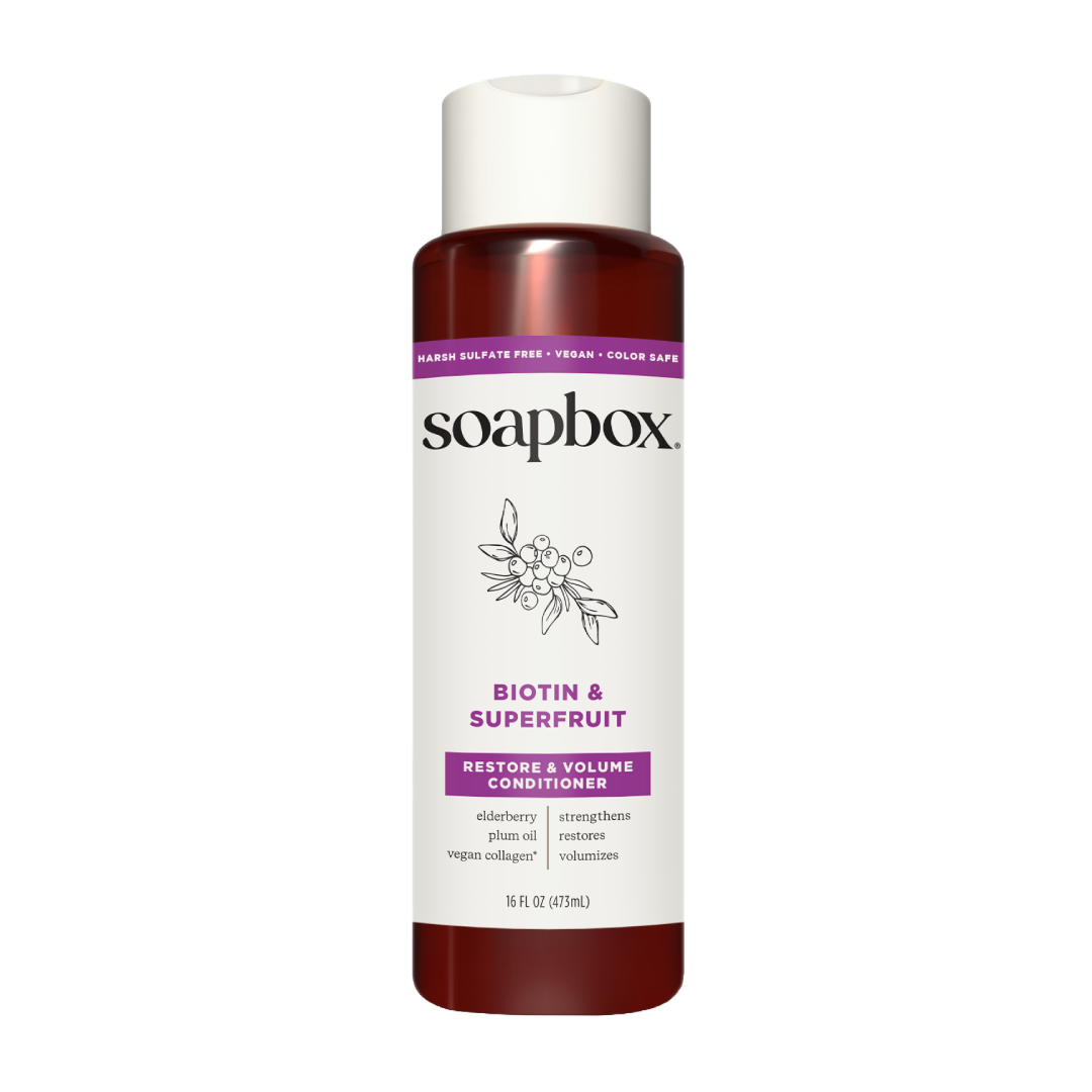 Soapbox Biotin & Superfruit Restore & Volume Conditioner bottle with white cap and burgundy liquid, 16 fl oz.