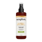 Soapbox Blowout Brilliance spray bottle with black pump top, amber glass container, and white label with gold text.