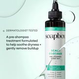 Dark glass bottle of Soapbox Scalp Soother pre-shampoo rinse-out treatment with turquoise and white label.