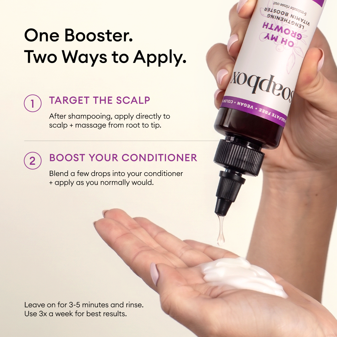 Hand holding white hair booster bottle with dropper applicator and product being dispensed onto palm.