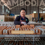 Worker in apron arranging bars of soap on table in factory warehouse.