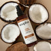 Soapbox Mane Tamer leave-in conditioner spray bottle surrounded by halved coconuts on beige background.