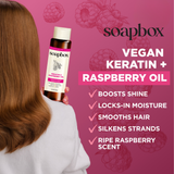 Person holding Soapbox vegan keratin and raspberry oil conditioner bottle against pink background with raspberry illustration