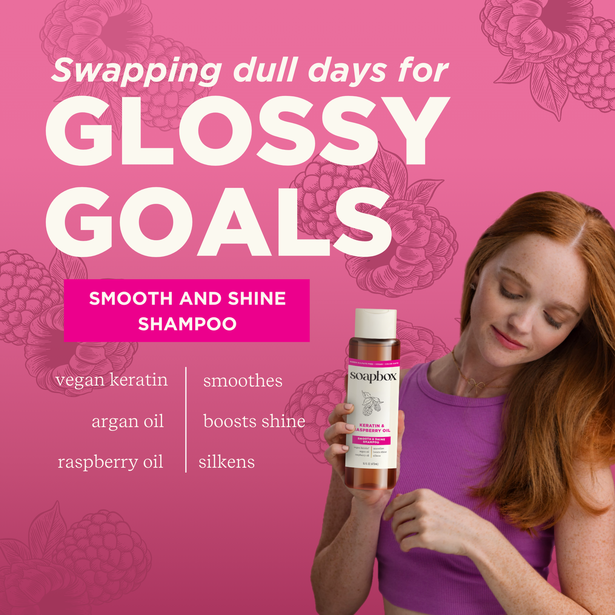 Woman with reddish-brown hair holding a Soapbox shampoo bottle against a pink background with raspberry illustrations.