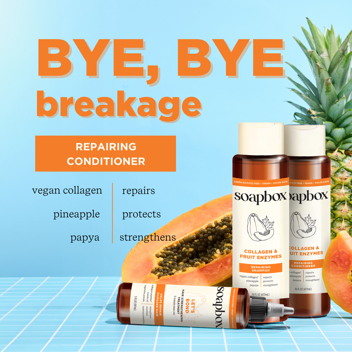 Soapbox Collagen & Fruit Enzymes Repairing Conditioner bottles with spray dispenser, papaya, and pineapple on blue background