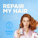 Woman with reddish-brown wavy hair holding a brown bottle spray treatment against a blue background.