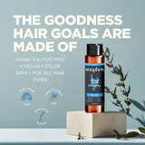 Soapbox scalp care shampoo and conditioner bottle with black cap displayed on cream pedestal with green botanical sprigs.