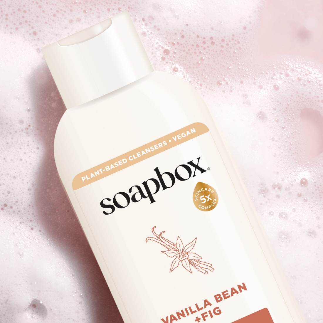 Soapbox body wash bottle with cream-colored label and vanilla bean plus fig text on pink sparkly background.