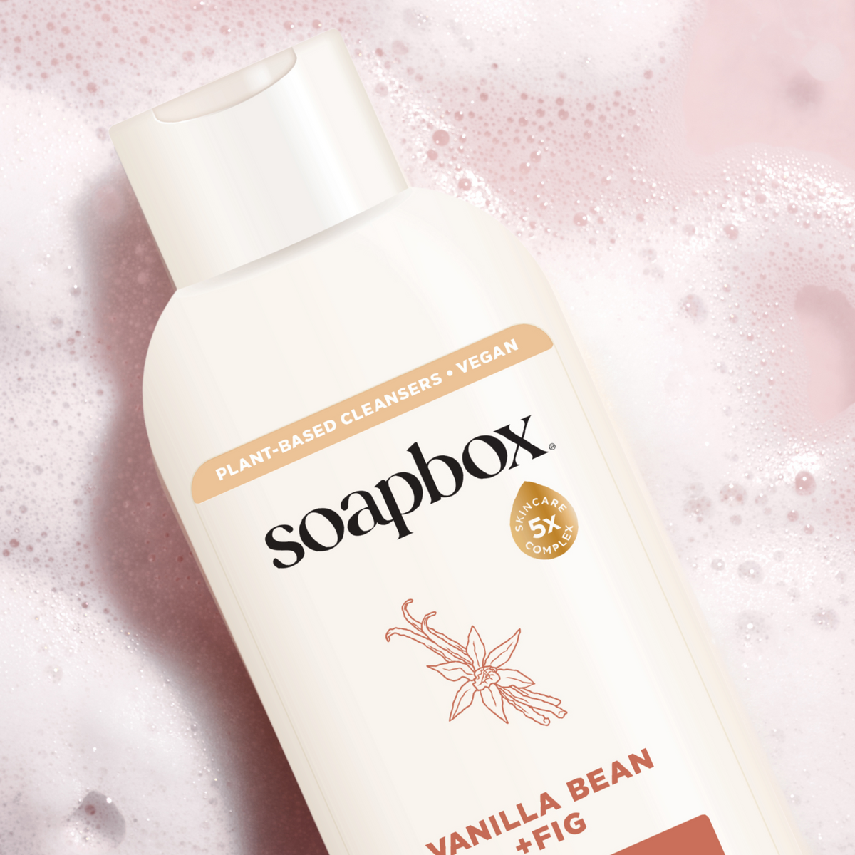 Soapbox body wash bottle with cream-colored label and vanilla bean plus fig text on pink sparkly background.