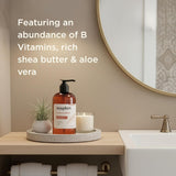 Amber bottle of vanilla bean hand soap with black pump dispenser on concrete tray next to candle and potted plant.