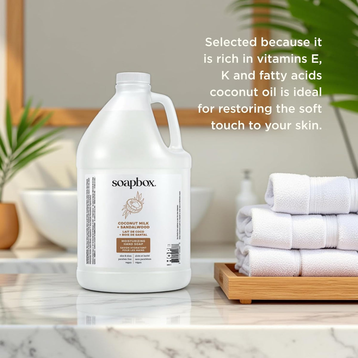 White gallon bottle of Soapbox liquid hand soap with white cap, displayed next to folded white towels on marble countertop.