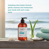 Soapbox liquid hand soap bottle with black pump dispenser next to aloe plant, folded towels, and seashells on wooden surface 