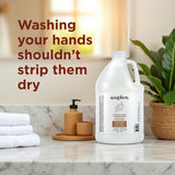 Large white plastic gallon bottle of Soapbox liquid hand soap with white cap on marble bathroom counter next to wooden access