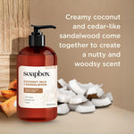 Red pump bottle of Soapbox coconut milk and sandalwood hand soap with coconut pieces and wood elements on beige background.