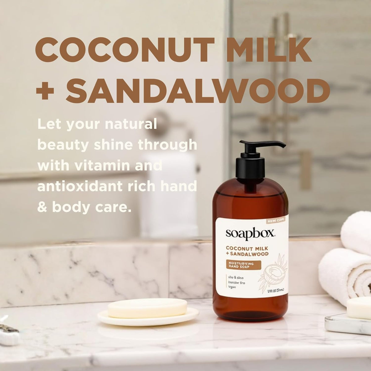 Amber glass pump bottle of Soapbox Coconut Milk + Sandalwood hand soap on marble bathroom counter with white soap dish and to