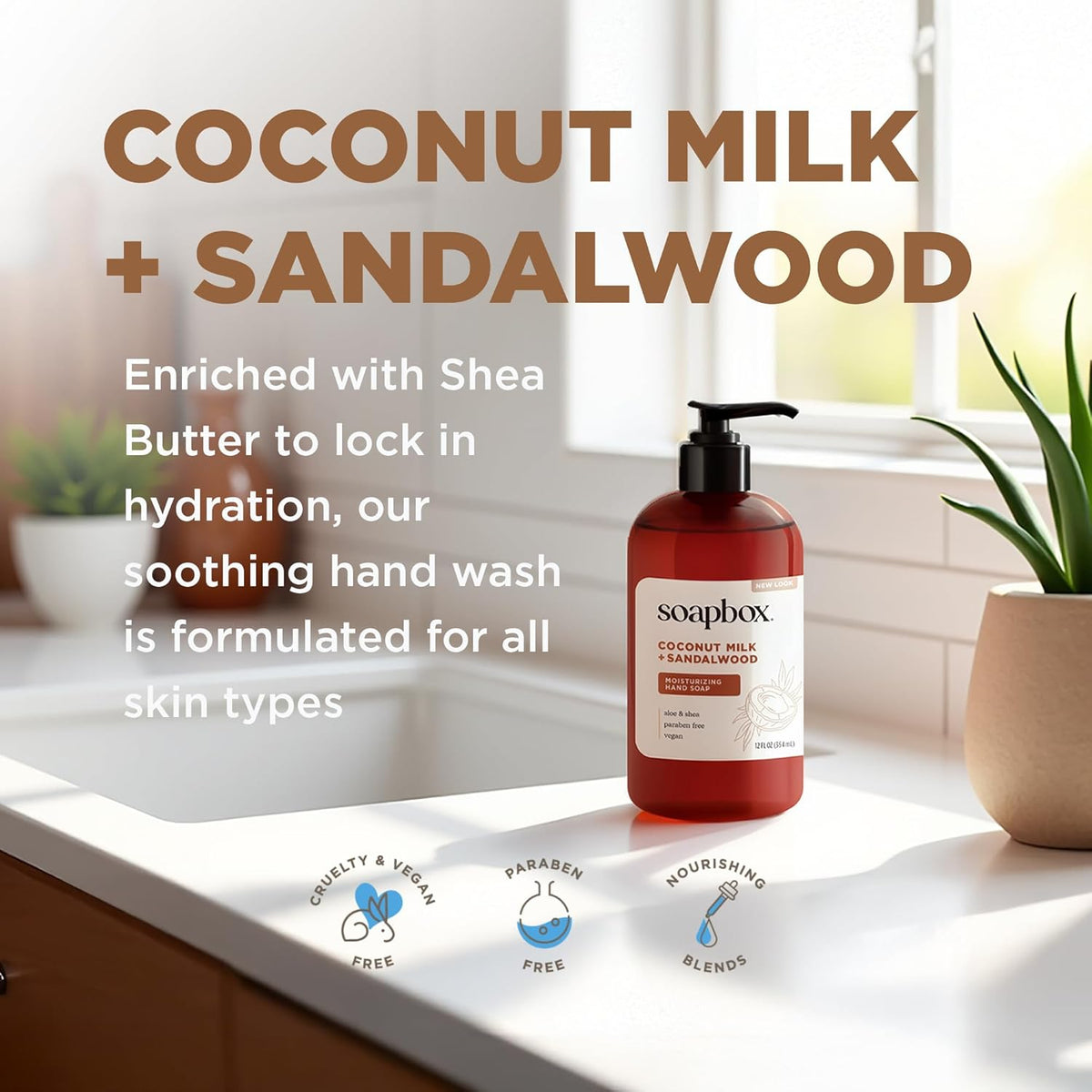 Amber pump bottle of Soapbox Coconut Milk + Sandalwood hand soap displayed on a white countertop with potted plants.