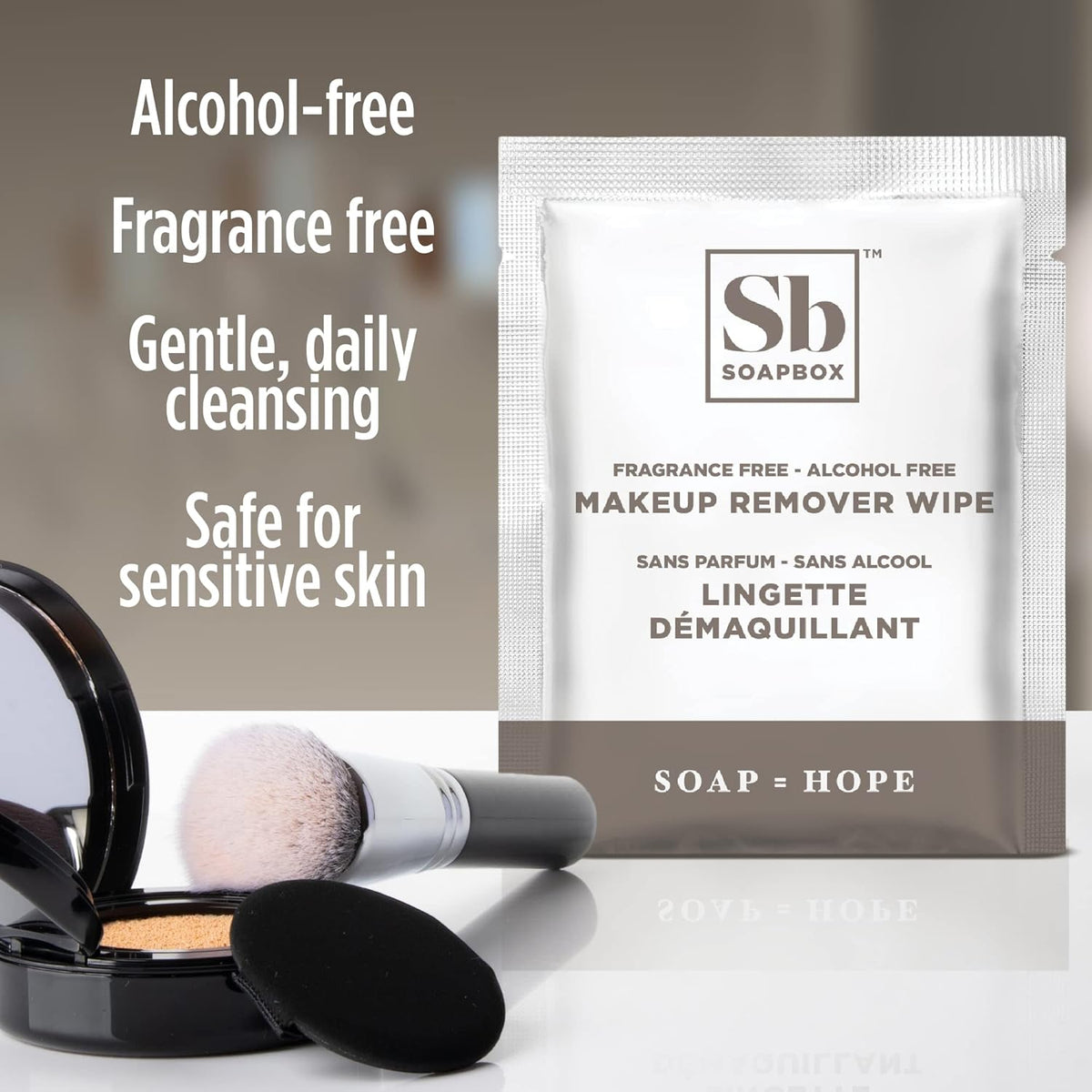 Soapbox fragrance-free makeup remover wipe packet displayed next to cosmetic brush and compact powder.
