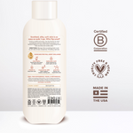 Cream-colored body wash bottle with white cap, displaying ingredient information, B Corporation certification, and "Made in t