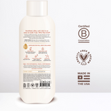 Cream-colored body wash bottle with white cap, displaying ingredient information, B Corporation certification, and "Made in t