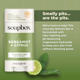 Soapbox bergamot and citrus aluminum-free deodorant stick with white cap next to lime slice and leaves on green background.