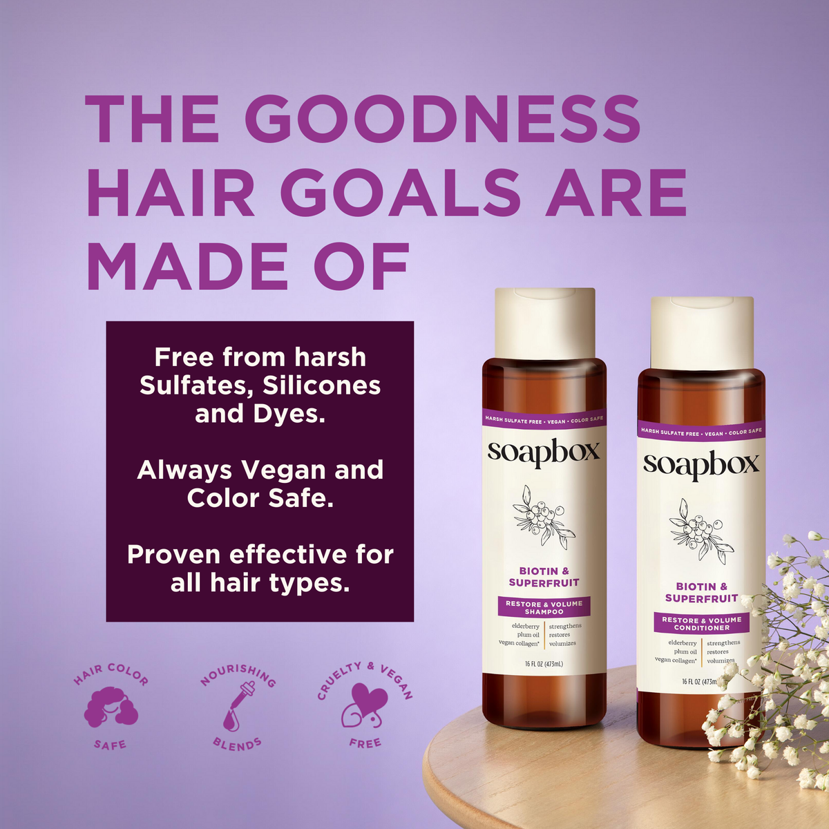 Two brown glass bottles labeled Soapbox Biotin & Superfruit shampoo and conditioner on a wooden surface with white flowers ag