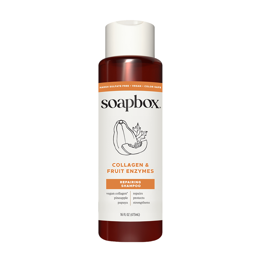 Soapbox bottle with white cap containing amber-colored liquid, labeled "Collagen & Fruit Enzymes Repairing Shampoo" with frui