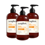 Three amber glass pump bottles of Soapbox Sweet Orange Citrus Moisturizing Hand Soap with black pump dispensers.