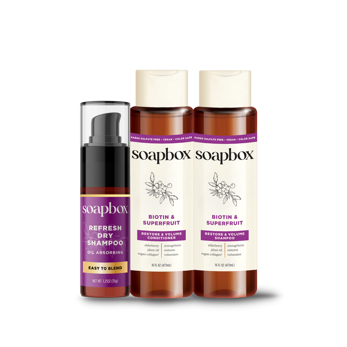 Three Soapbox haircare products: dry shampoo spray, shampoo, and conditioner in amber bottles with purple labels.