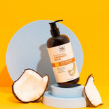 Dark brown bottle with pump dispenser of Softening Coconut Milk Deep Moisture Body Lotion, flanked by fresh coconut halves on
