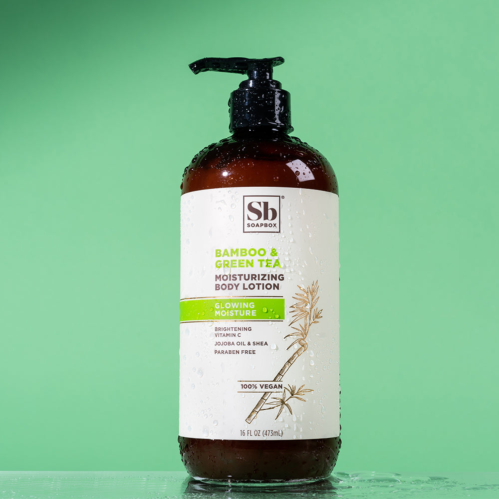 Brown bottle with black pump dispenser labeled "Bamboo & Green Tea Moisturizing Body Lotion" by Soapbox on mint green backgro