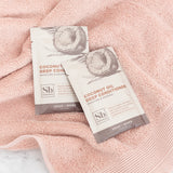 Two white sachets with coconut illustrations and "Coconut Oil Deep Conditioner" text on pink towel.