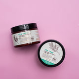 Two jars of tea tree soothing hydration hair mask with black lids on a pink background.